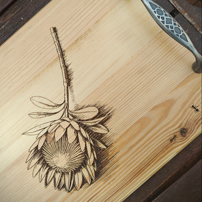Wooden surface with a engraved floral design and metal handle.
