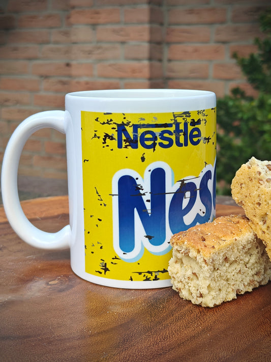 White mug with Nestle Nesquik label on a wooden surface with cookies.