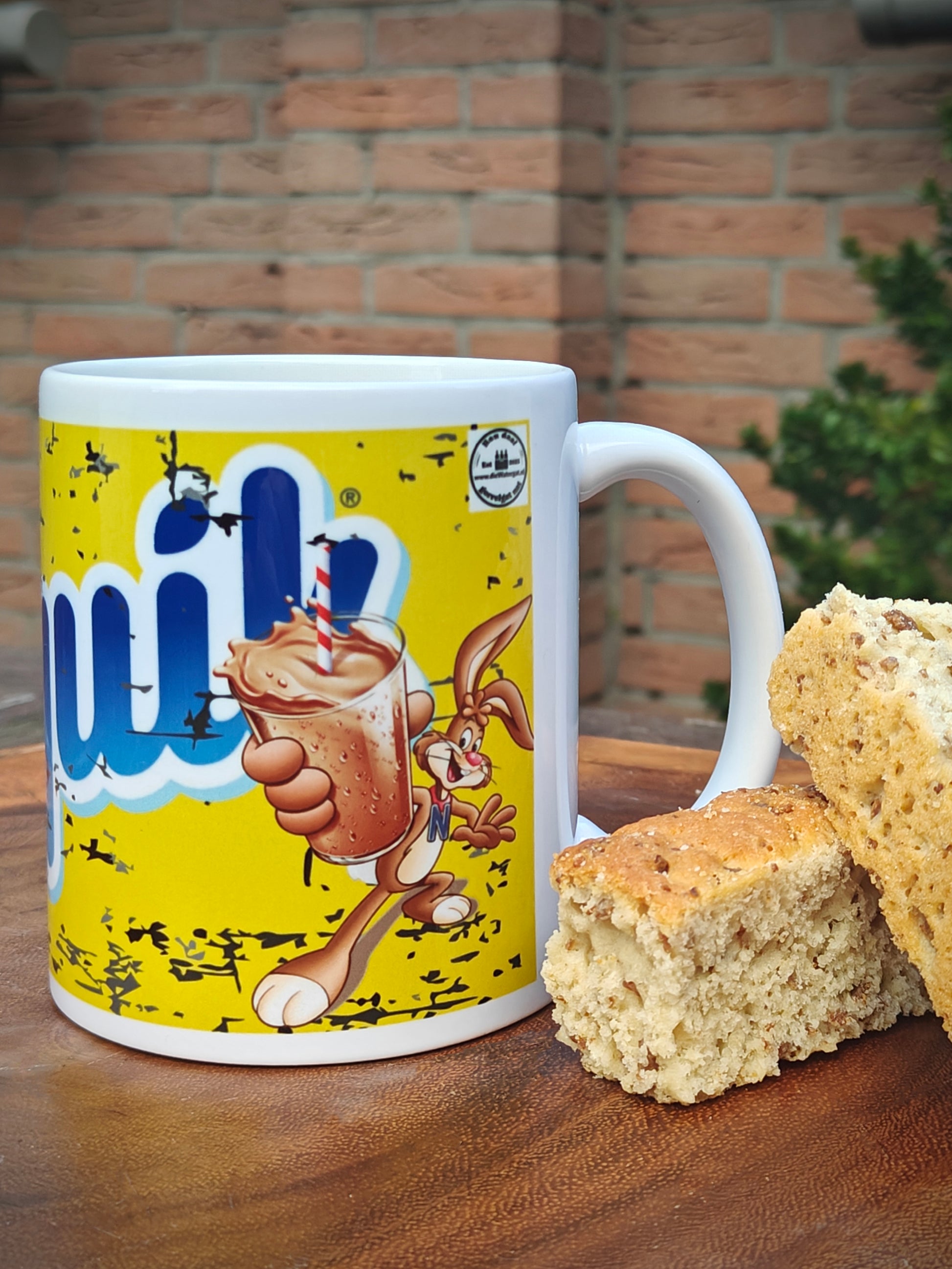 Mug with a cartoon character design on a wooden surface with Rusks.